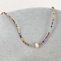 Detail of colorful beaded necklace with freshwater pearl on a minimalist ceramic edge - Rainbow Beads
