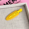 Close-up of matte yellow hair clip on a beige woven tray with soft lighting - Duckbill Hair Clips / Egg Yolk Yellow