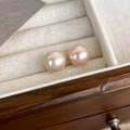Primer plano de pendientes de perlas redondas rosa champán con brillo en un joyero - 12mm / Rosa Champaña (12mm)