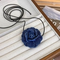 Dettaglio del ciondolo a rosa in denim blu su una collana a cordoncino nero in un vassoio - Piccolo / Blu scuro