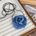Dettaglio del choker a camelia in denim blu con petali sfilacciati in un vassoio per gioielli - Grande / Azzurro