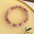 Detailansicht des rosa Erdbeerquarz-Perlenarmbands mit natürlicher Textur auf Display - Lila Mehrfarbig (23707C)