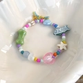 Nahaufnahme eines bunten Perlenarmbands mit Herz- und Sternanhängern in weißer Schale - Knochen und Fisch