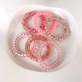 Detail of six spiral telephone cord hair ties in shades of pink on a white tray - Pink