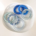 Close-up of 6 candy-colored spiral hair ties in blue floral and polka dot patterns - Blue
