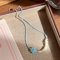 Primer plano del collar de cuentas con flor azul y perlas irregulares en bandeja tejida - Estilo de Perla con Flor Azul Claro (11# 22976)
