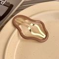 Macro di una clip per capelli a onda in resina moka con fermaglio in metallo oro - Nuvola Caffè