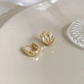 Primer plano de pendientes de aro dorados con textura acolchada en bandeja decorativa - Dorado