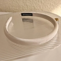 Détail du serre-tête en satin jacquard blanc avec étiquette faite main sur plateau - Blanc Cassé
