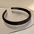 Close-up of black jacquard satin headband featuring handmade label and floral texture - Black