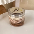 Dettaglio di elastici per capelli marroni in un barattolo cilindrico trasparente - Pois Caffè (23969J)
