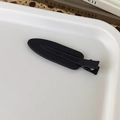 Macro detail of matte black duckbill hair clip on a minimalist decorative tray - Black