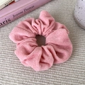 Close-up of a light pink plush scrunchie with soft terry cloth texture and fabric label - Light Pink