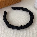 Macro view of black pleated satin headband showing rich texture and wavy fabric detail - Black