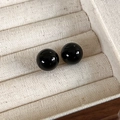 Gros plan de boucles d'oreilles boules noires polies dans un coffret à bijoux beige - Diamètre 12mm