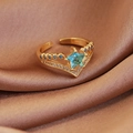 Macro shot of V-shaped gold crown ring with blue star zircon on satin fabric - Gold Blue Pentagram Star (23945)