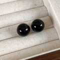 Gros plan de boucles d'oreilles boules noires polies dans un écrin en velours beige - Diamètre 14mm