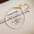 Dettaglio di eleganti perle bianche con chiusura a moschettone dorata e catenella regolabile - Bracciale di perle sottili