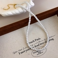 Dettaglio di collana con perle bianche e chiusura a moschettone dorata su supporto - Collana di perle medie