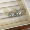 Vista macro di orecchini con perle tonde grigio argento in una scatola per gioielli beige - Orecchini a bottone da 12mm