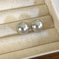 Primo piano di orecchini a perno con perle grigie in una scatola per gioielli in velluto - Orecchini a bottone da 14mm