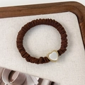 Détail du chouchou plissé marron foncé avec un pendentif en forme de cœur blanc doré - Cœur Café