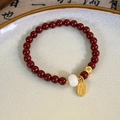 Detail of red beaded bracelet with golden Nafu charm and white bead on ceramic tray - Small White Bead Fortune Charm
