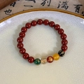 Close-up of red beaded bracelet with engraved lotus and golden mantra charms - Large Red Green Gold Text Beaded