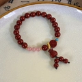 Detailed close-up of a red cinnabar-style beaded bracelet with a symbolic lotus pendant - Large Fortune Bag Lucky Charm