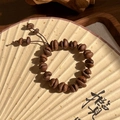 Dettaglio del bracciale artigianale con chicchi di caffè e cordino su un ventaglio - Stile Chicco di Caffè Base