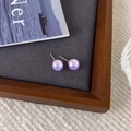 Vue détaillée des boucles d'oreilles perles irisées violettes avec tiges en métal argenté - Violet
