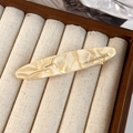 Detail of cream acetate hair clip with marble texture and Creation France engraving - Jasper White (24170A)