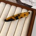 Close-up of amber tortoiseshell acetate hair clip on a wooden jewelry display tray - Tortoiseshell (24170D)
