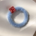 Detail of light blue fuzzy scrunchie with high elasticity and a small red mushroom label - Blue