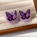 Close-up of purple resin butterfly earrings with gold foil and soft plush pom poms - Purple