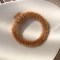 Detail of brown fuzzy scrunchie with whale leather tag in a white ceramic dish - Light Coffee