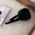 Detail of a fluffy black plush ball hair clip with a gold handmade metal tag on top - Black Pom Pom Black Clip