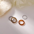 Flat lay detail of four-piece rings set with amber resin and silver chain texture - Brown