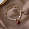 Nahaufnahme der Perlenkette mit Goldperlen und einem natürlichen roten Rosenknospenanhänger - Weißes Armband / Weiß
