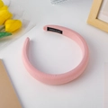 Detail of pink padded sponge headband featuring a woven handmade label on light fabric - Pink