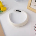 Close-up of white sponge headband with handmade label on bright minimalist background - White