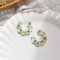 Macro detail of C-shaped resin earrings featuring embedded green and yellow dried flowers - Blue-Green Floral Style / Teal