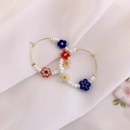 Detalle de flores de resina de colores y cuentas blancas en un pendiente de aro dorado - B Estilo Aro