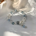Détail du bracelet perlé avec cristaux bleus, breloque fleur et accents dorés - Bleu