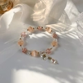 Detail showing a crystal beaded bracelet with shell flowers on white satin fabric - Pink
