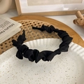 Detail view of a black pleated headband with oversized bow style for hair volume - Black