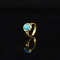 Golden ring with a round turquoise gemstone featuring natural veins on black background - Gold Tone Turquoise