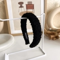 Dettaglio del cerchietto nero fatto a mano in maglia bouclé con texture morbida e calda - Nero