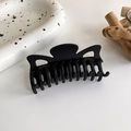 Gros plan d'une grande pince à cheveux noire mate sur une surface blanche minimaliste - Grand Style Incurvé Mat (13# 18060)