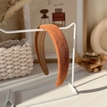 Close-up of caramel padded headband with textured knit fabric on white metal stand - Caramel Orange Knitted (1# 17724B)